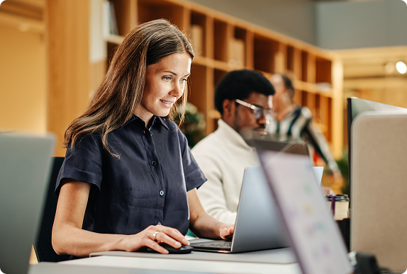 Profissional trabalhando em laptop em ambiente corporativo moderno